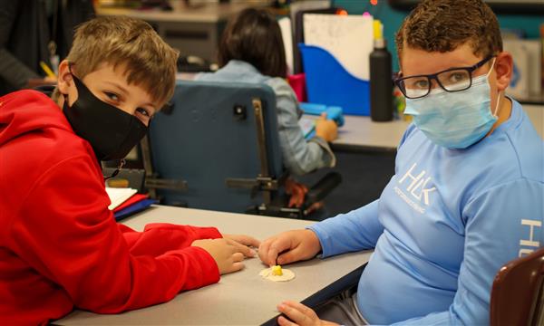 Two boys smile while making a fossil in a cup